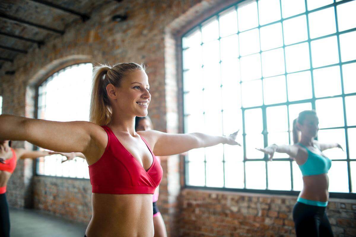 Woman with arms out stretched exercising while looking happy