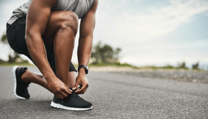 Picture of a man lacing up his running shoes.